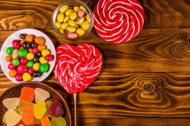 Different sweet candies on rustic wooden table Top view