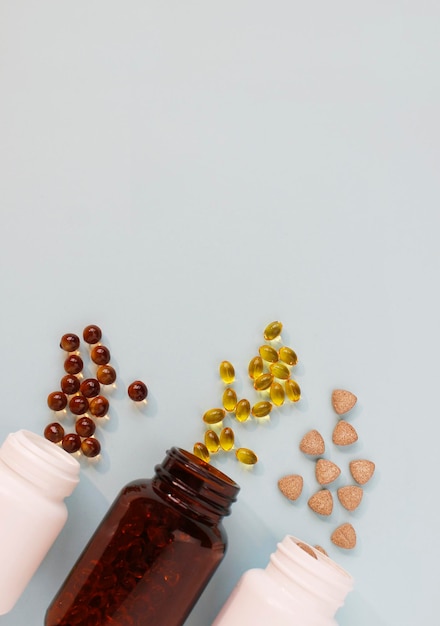 Different tablets, capsules, pills are scattered from the jar on a light background The concept of health Minimalism