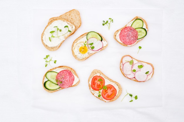 Different tapsas sandwiches with vegetables on white background top view