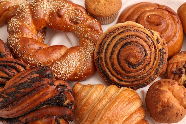 Different tasty freshly baked pastries on white tablecloth flat lay