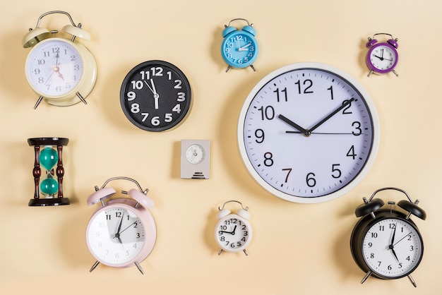 Photo different type of hour glass; clocks and alarm clocks on beige background