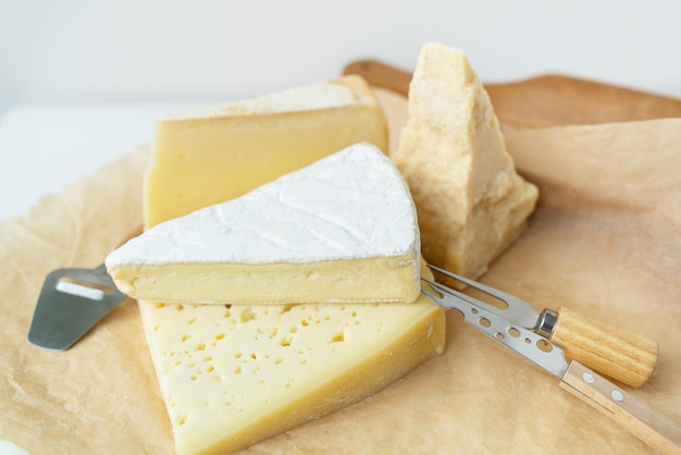 Different types of cheese lie on top of each other with cheese knives A delicious delicacy