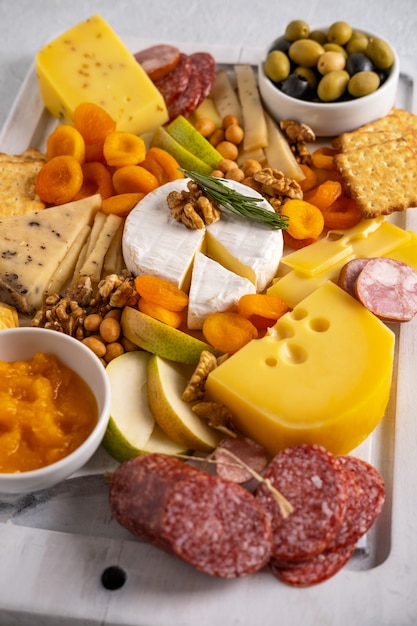 Different types of cheeses  and cold cut meats. Top view on a white background. Assorted cheeses with nuts, cracker,  olives, salami  and rosemary.