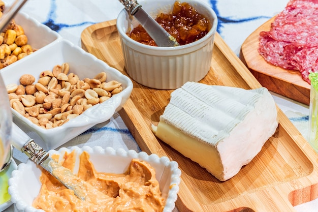 Different types of cheeses, wines, baguettes, fruits and snacks on the table for tasting and holiday scenery.