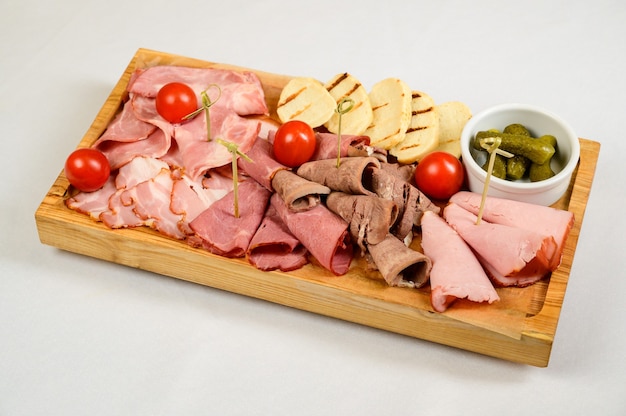 Different types of chopped sausages on a wooden board on white background