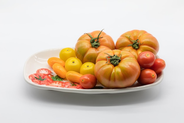 Different types of colorful tomatoes in a font on a white background