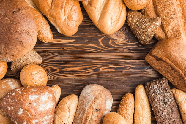 Different types of delicious breads on wooden desk