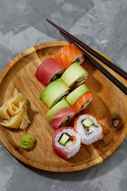 Different types of delicious and juicy sushi and rolls on a wooden board