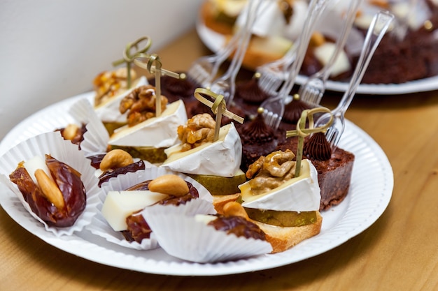 Different types of desserts with biscuits and walnuts on the white plate.