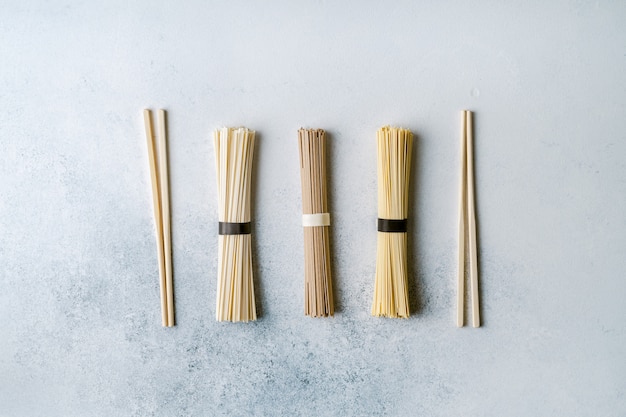 Different types of dry long asian noodles and chopsticks