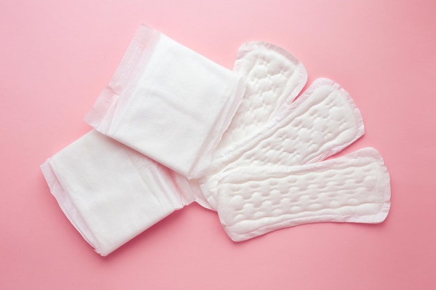 Different types of female pads during the menstrual cycle on a pink background