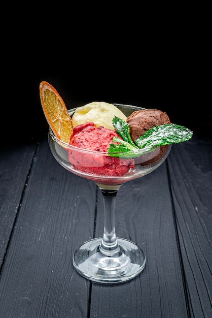 Different types of ice cream in a glass glass on a dark background