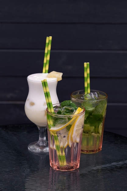 Different types of mojito cocktail on cafe background.