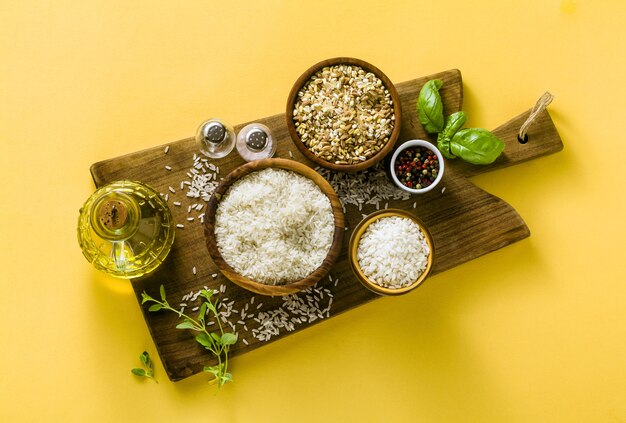 Different types of rice on a wooden board made from olive wood.  with basil leaves and olive oil. healthy home cooking