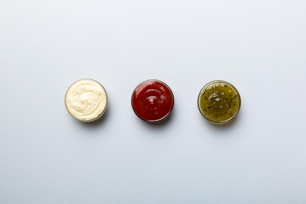 Different types of sauces in bowls on a colored Board Top view various sauces copy space