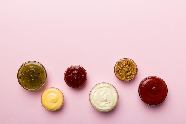 Different types of sauces in bowls on a colored Board Top view various sauces copy space