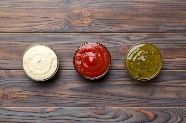 Different types of sauces in bowls on a colored Board Top view various sauces copy space