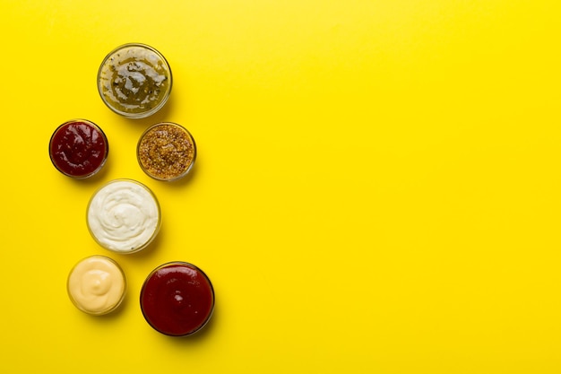 Different types of sauces in bowls on a colored Board Top view various sauces copy space