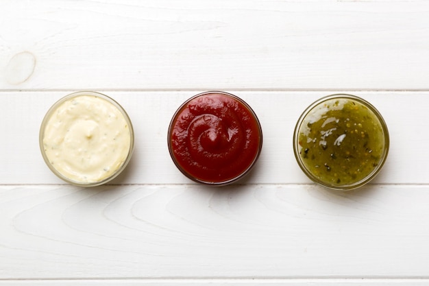 Different types of sauces in bowls on a colored Board Top view various sauces copy space