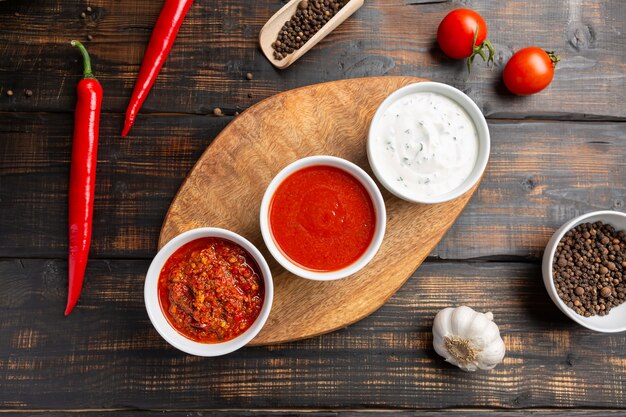 Different types of sauces in bowls on cutting Board with garlic. On dark rustic