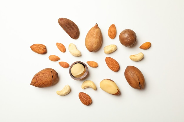 Different types of tasty nuts on white background