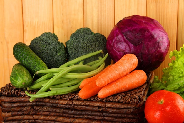 Different vegetables on basket on wooden background