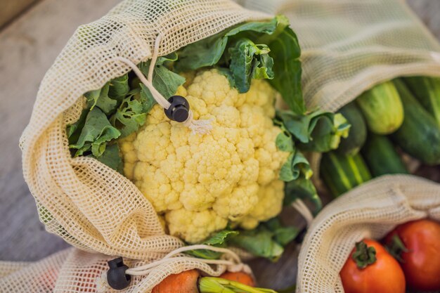 Different vegetables in reusable bags on wooden background zero waste concept