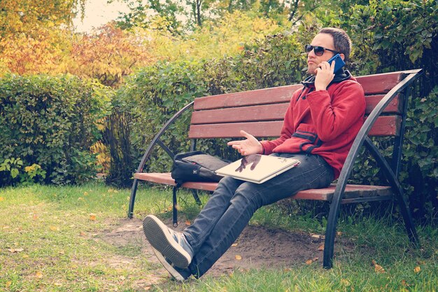 Difficult business conversation on the phone solving problems at work dissatisfied man working on laptop computer Talking on smartphone sitting in park discontent dissatisfaction displeasure