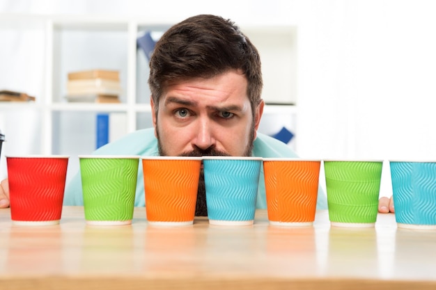 Difficult choice decisionmaking serious and sad man with colorful coffee cups Many cups of coffee hard choice to make i need more coffee low energy Taking decisions mature hipster man