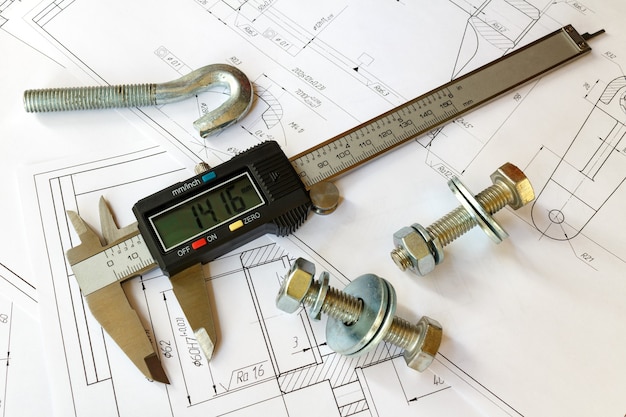 Digital caliper with bolts and nuts on engineering drawings