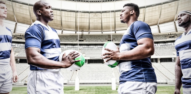 Digital composite image of team of rugby players facing each other while holding rugby ball in sport