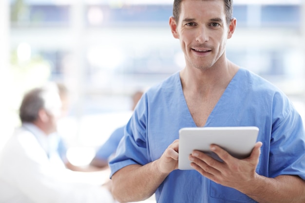 Digital doctor A medical professional working on a touchpad with colleagues sitting in the background