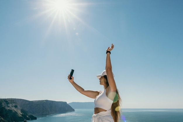 Digital nomad woman in the hat a business woman with a laptop sits on the rocks by the sea during