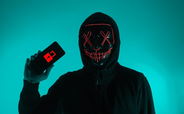 Digital security Concept Anonymous hacker with mask holding smartphone hacked