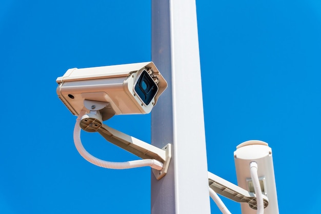 Digital surveillance camera is mounted on a pole with the blue sky in the background.