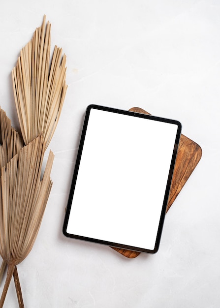 Digital tablet computer with isolated screen on office desk at home interior with palm leaves