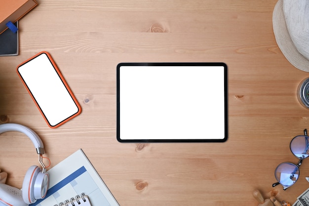 Digital tablet, eye glasses, headphone, coffee cup, smart phone and notebook on wooden background.