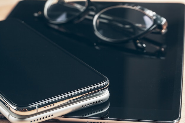 Digital tablet and mobile phone. Electronic devices on wooden table, close up.