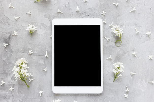 Digital tablet on spring floral background with white lilac flowers