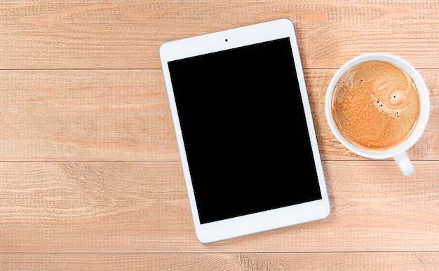 Digital tablet with copy space and coffee mug on wooden table