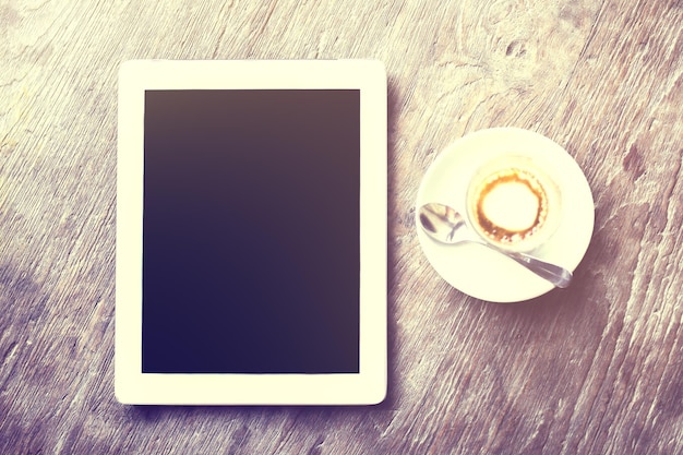 Digital tablet with cup of coffee on a wooden table