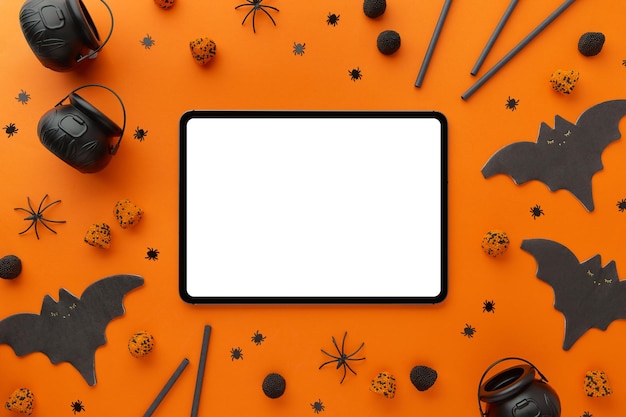 Digital tablet with halloween decor on an orange black background