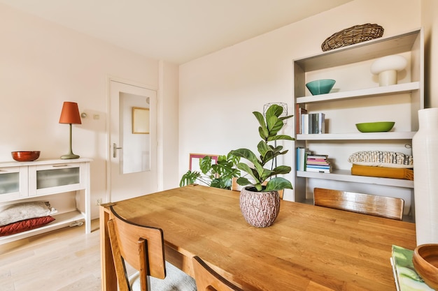 A dining room with a wooden table and a plant