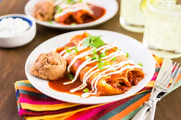 Photo dinner plate with chicken enchiladas garnished with green onions and sour cream.