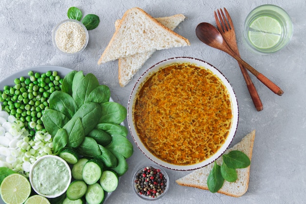 Dinner table top view with delicious soup and healthy green salad on stone background