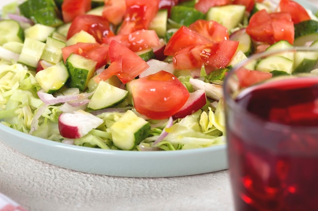 Dinner table with vegetable salad and red wine in a glass