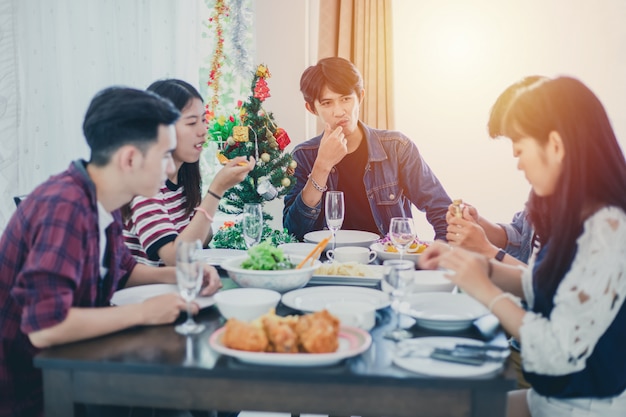 Dinner with Asian Group of best friends enjoying evening drinks while sitting at the dinning table on the kitchen together