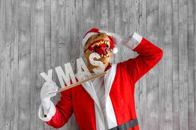 Photo dinosaur dressed up as santa claus with xmas sign with hands on head