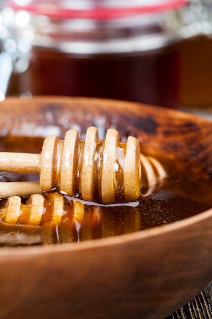 Photo dipped in honey specially made from wood homemade coarse spoon, sweet bee honey and wooden spoon that allows you to transfer and pour honey without dripping and spreading