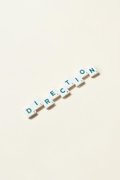 Direction formed of scrabble blocks on beige background